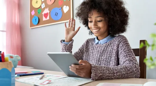 Girl raising her hand while on a video call for school.