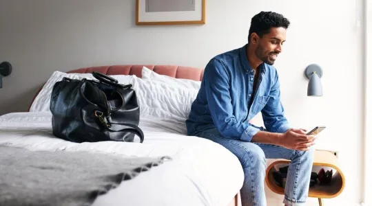 Man sitting on bed in guestroom | Merry Maids