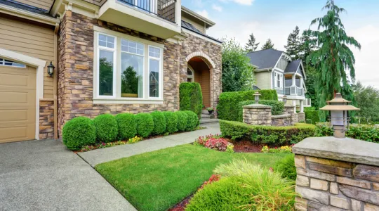 Beautiful curb appeal of American house with stone trim and perfectly trimmed shrubs | Merry Maids