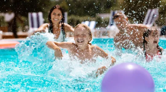 Young child playing in a pool with mom and sister | Merry Maids