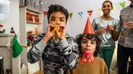 Family celebrating the new year. Kids using whilst blowing streamers and counting down to the new year | Merry Maids