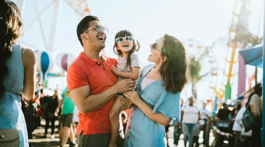 A cute mixed race family enjoys the rides and sun at the fair activities on Santa Monica Pier | Merry Maids