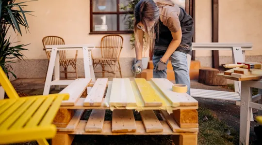 Woman spraying outdoor furniture with a protectant spray to preserve it from the elements. | Merry Maids