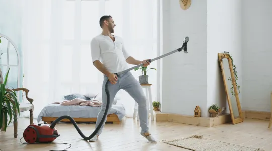 Man playing air guitar on vacuum while cleaning house