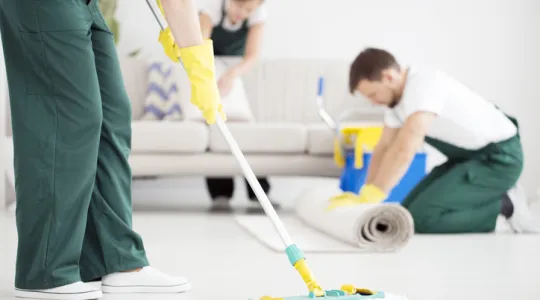 Cleaning professionals doing a thorough job mopping floors and vacuuming upholstery at a residence. | Merry Maids®