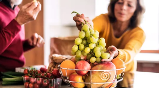 Couple eating fruit in kitchen