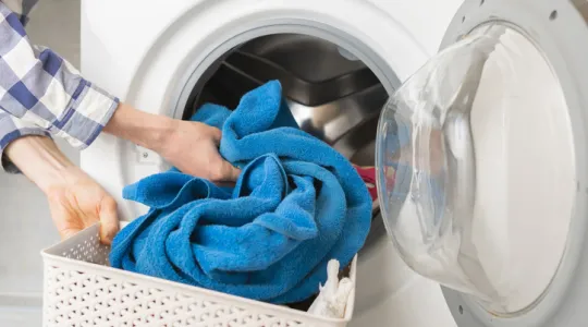 Person’s hand put dirty clothes in the washing machine | Merry Maids