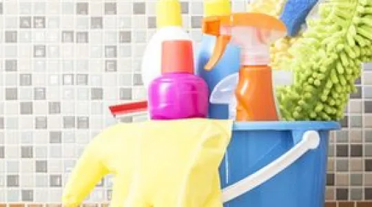 A blue bucket containing cleaning supplies on a counter
