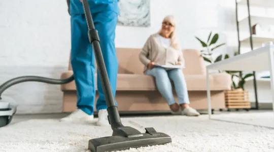 Professional cleaner vacuuming for an elderly woman | Merry Maids