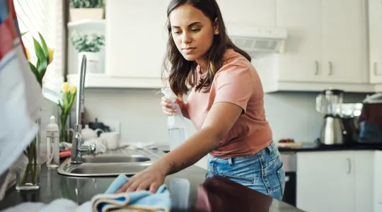 Young woman cleaning the countertops in her kitchen. | Merry Maids®