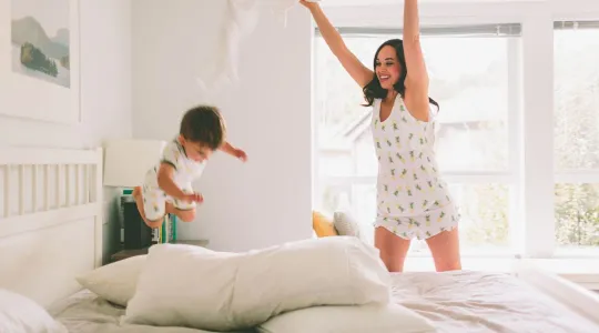 Mother and child play on freshly-made white bed