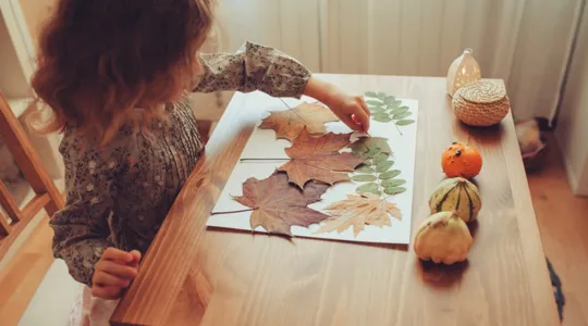 Little girl creating leave collage at desk | Merry Maids