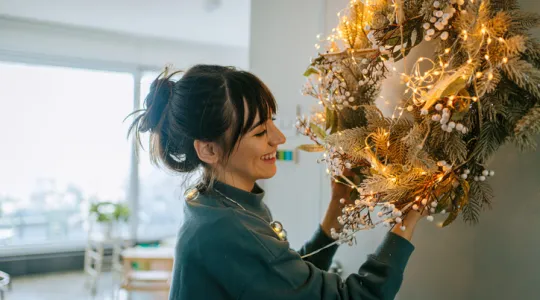 Young woman hanging a wreath on the living room wall | Merry Maids