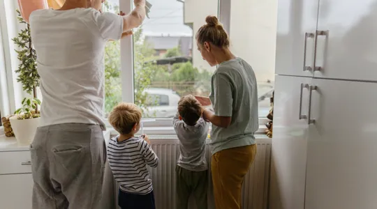 Young children helping their parents with chores in the morning before school. They are helping wipe down windows while watching for the school bus. | Merry Maids