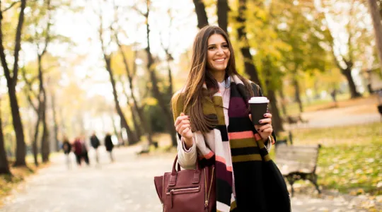 Pretty young woman with coffee cup in the autumn park | Merry Maids