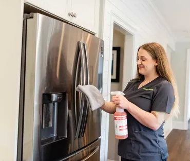 Merry Maids team member cleaning fridge