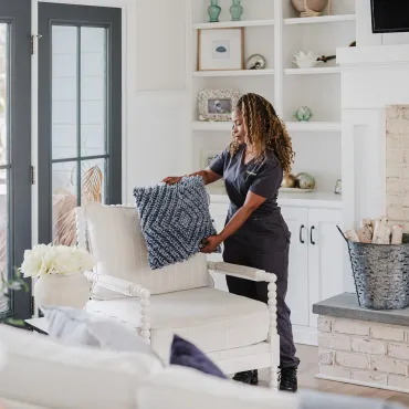 Cleaner fluffing pillows in living room