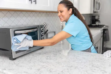 Merry Maids cleaner wiping microwave