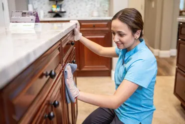 Merry Maids team member wiping cabinets