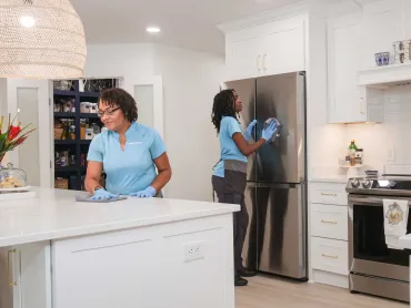 Two Merry Maids team members cleaning kitchen