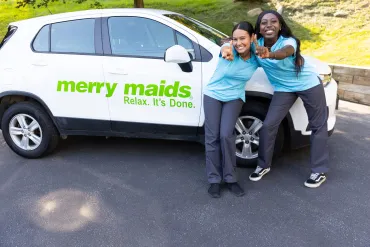 merry maids posing beside a merry maids branded vehicle