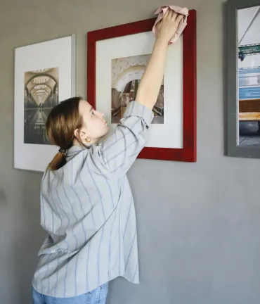 woman dusting a picture frame