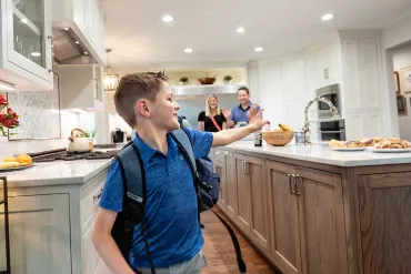 Boy waving to family in kitchen