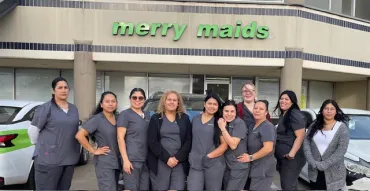 merry maids team standing in front of their storefront