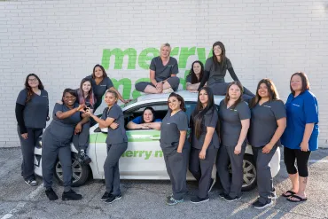 merry maids team posing with a branded vehicle