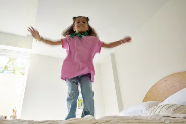 little girl jumping on bed