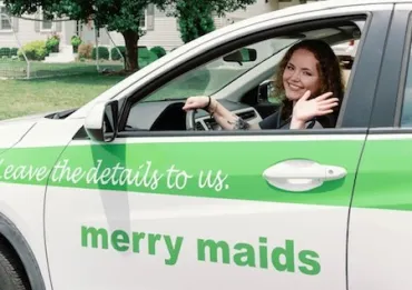 merry maids posing by branded vehicles